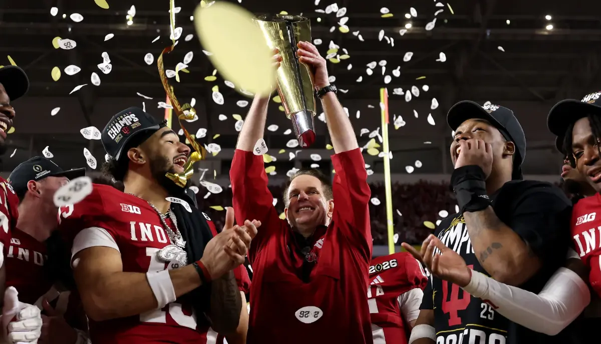 Members of the Indiana University football team lift their championship trophy